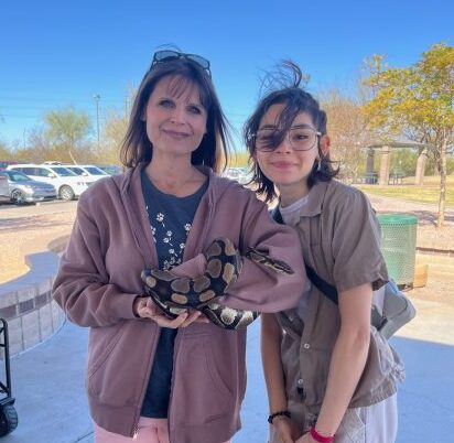 La profesora de Ciencias Veterinarias Jessica Berger y la estudiante de ISAZ Linda Hernández observan a un invitado especial resbaladizo en el Día de Diversión Familiar.